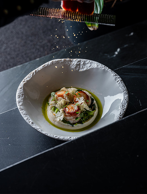 Plat raffiné de Saint-Jacques servi avec une émulsion et des légumes croquants au restaurant Dans le Noir ?
